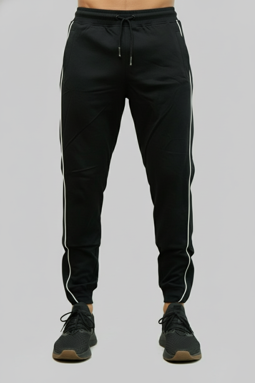 Black jogger pants with white stripes worn by a person on a gray background